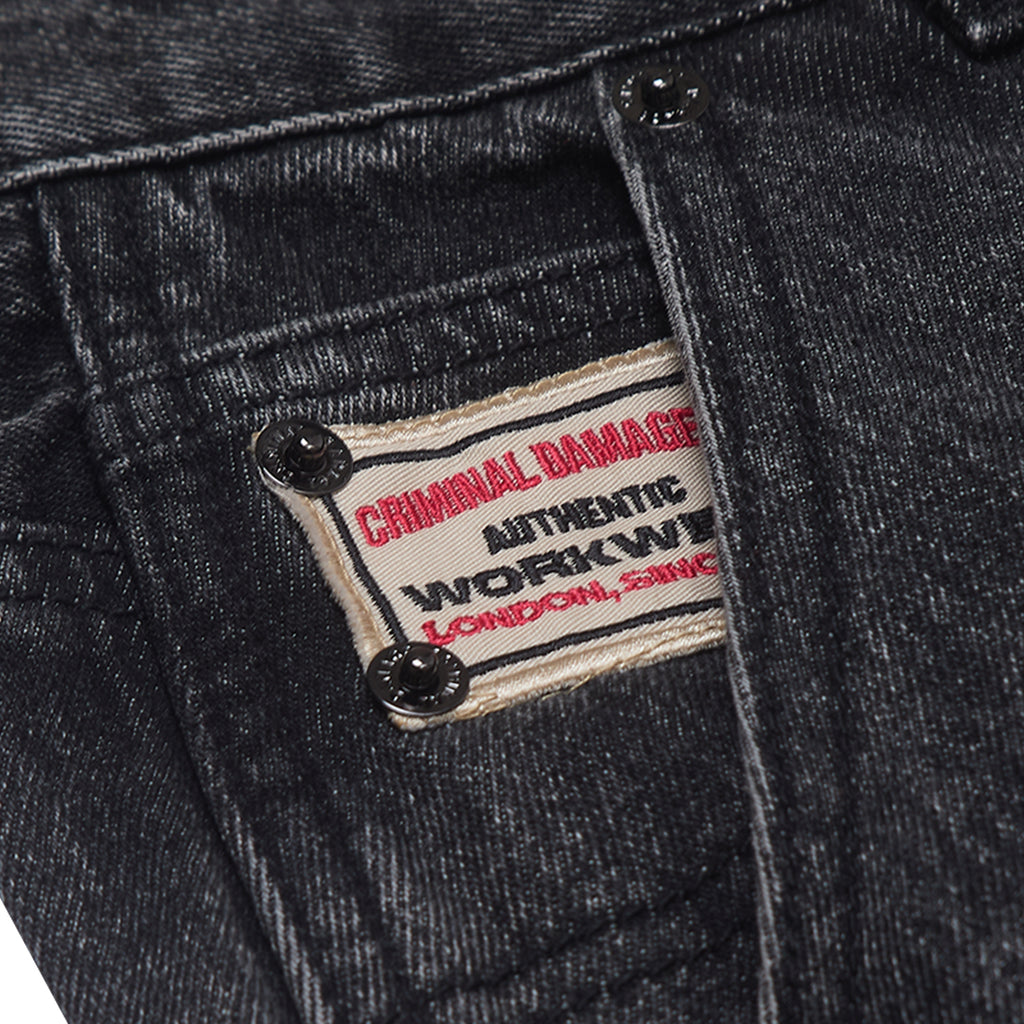 Close-up of a denim jacket with a 'Criminal Damage' label.