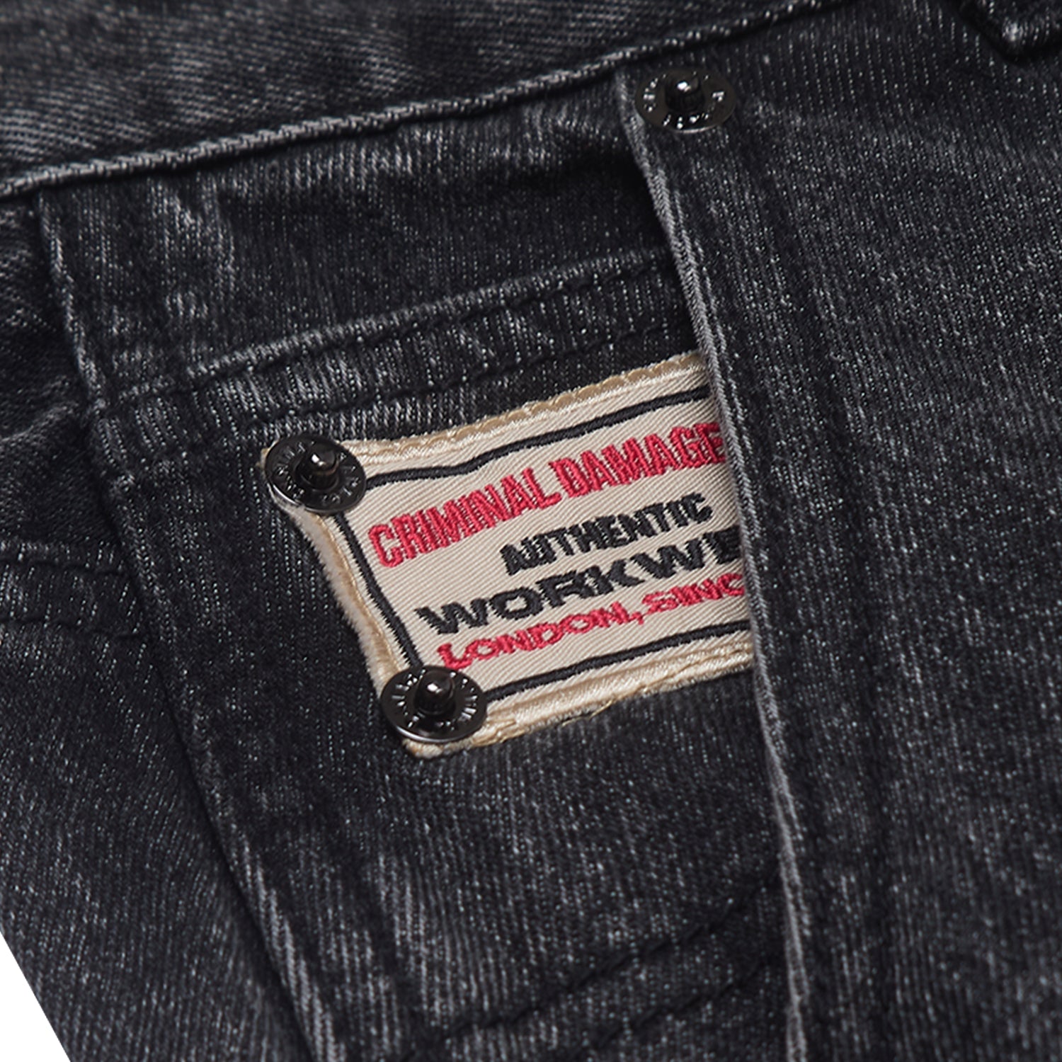 Close-up of a denim jacket with a 'Criminal Damage' label.