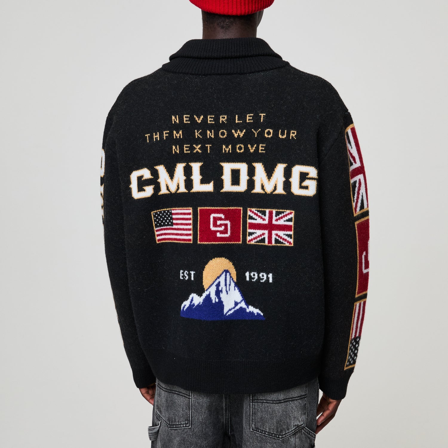 Black sweater with text and flags on the back, worn by a person.