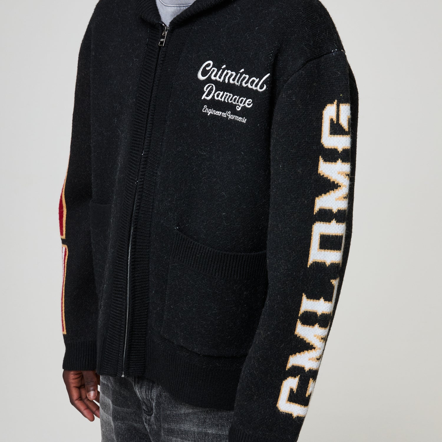 Black zip-up hoodie with 'Criminal Damage' branding on a gray background