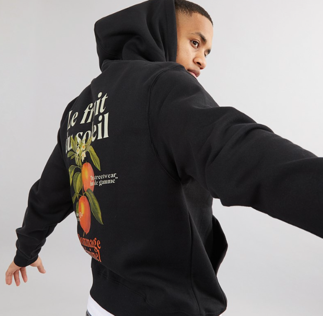 Person wearing a black hoodie with a graphic design on the back against a plain background