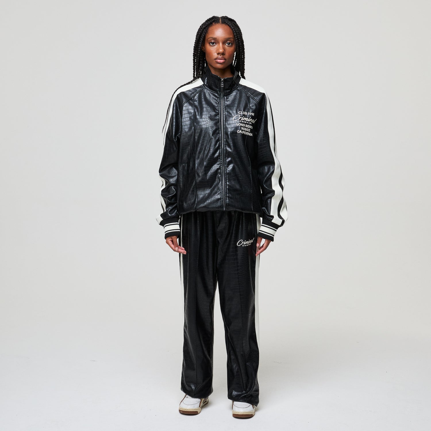 Person wearing a black tracksuit with white stripes on a white background