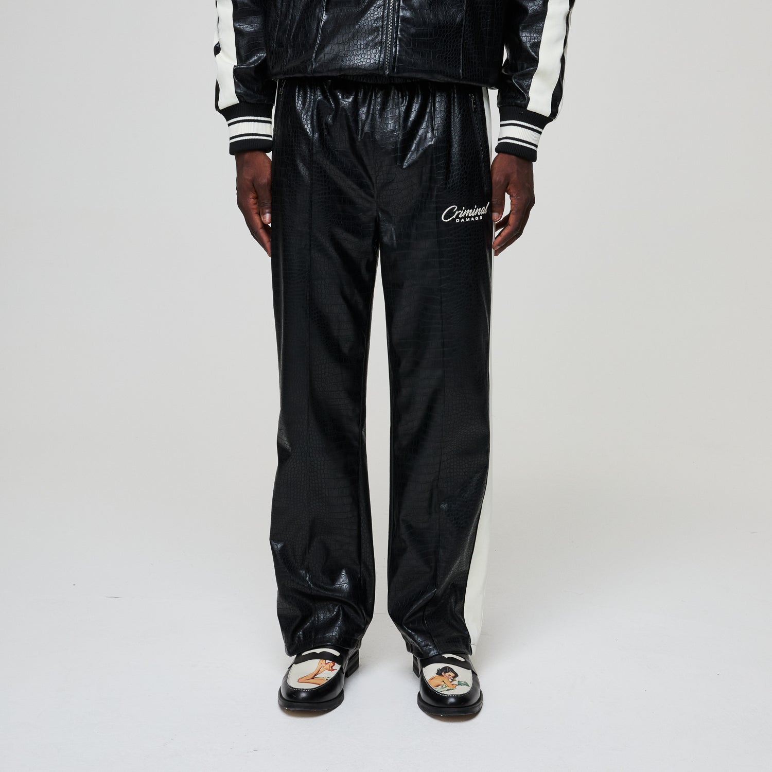 Black tracksuit with 'Criminal Damage' branding on a white background