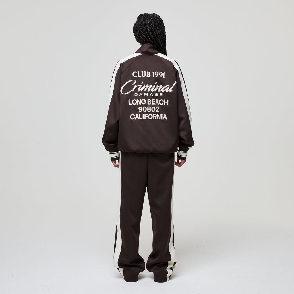 Person wearing a black tracksuit with white text on the back against a gray background