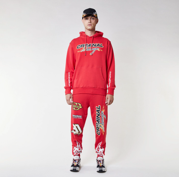 Model wearing a red Criminal Damage hoodie and pants on a white background