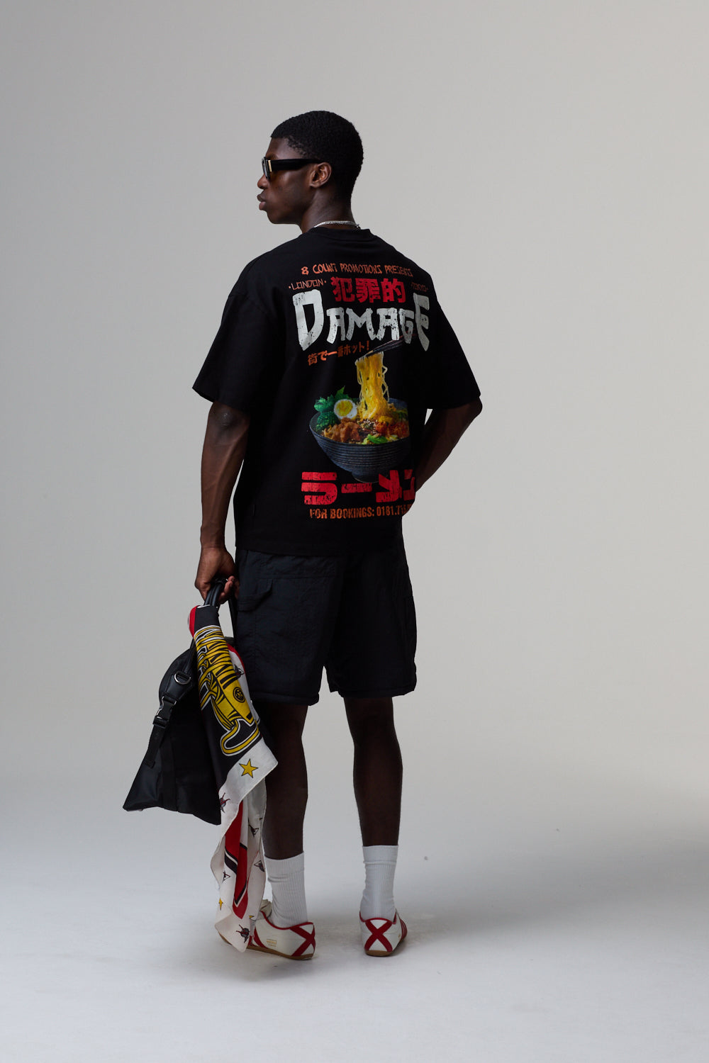 Model wearing a black Criminal Damage graphic t-shirt with colourful design on a grey background