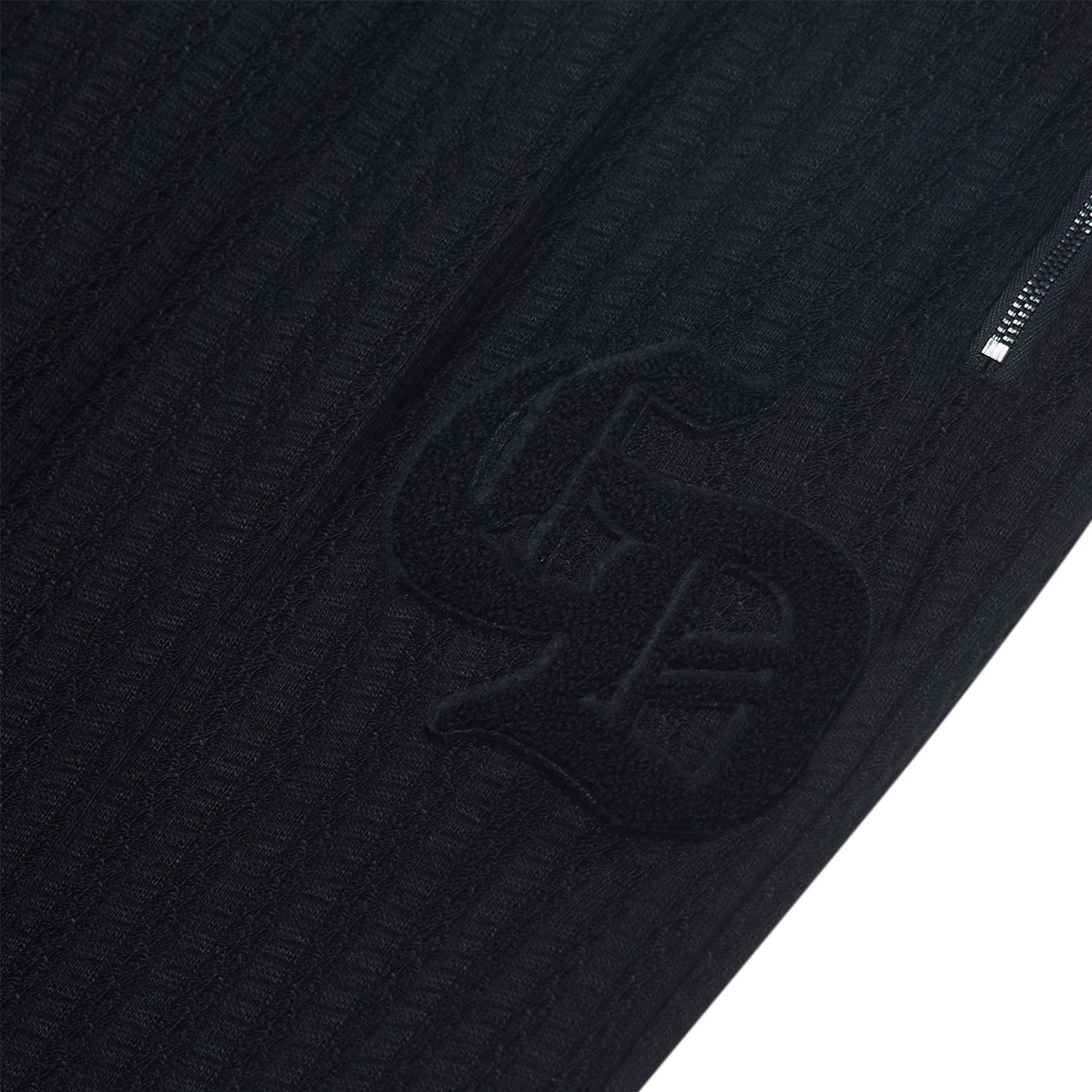 Close-up of a textured black jacket with a logo on a white background