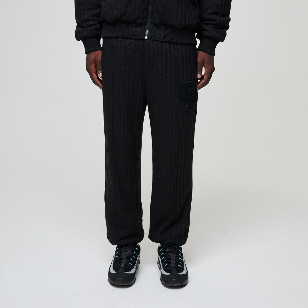Person wearing black ribbed knit pants on a white background
