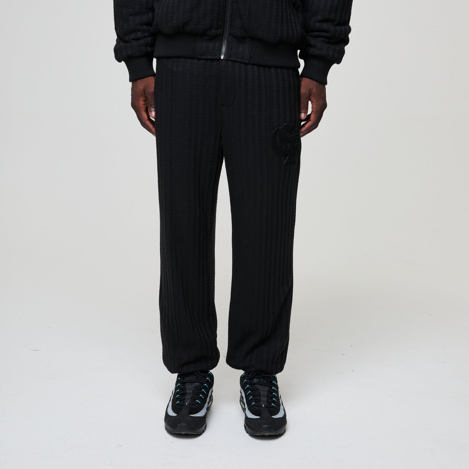 Person wearing black ribbed knit pants on a white background