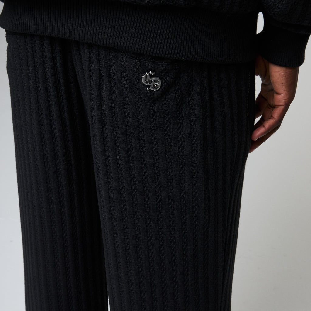 Black ribbed knit pants with a logo on a plain background