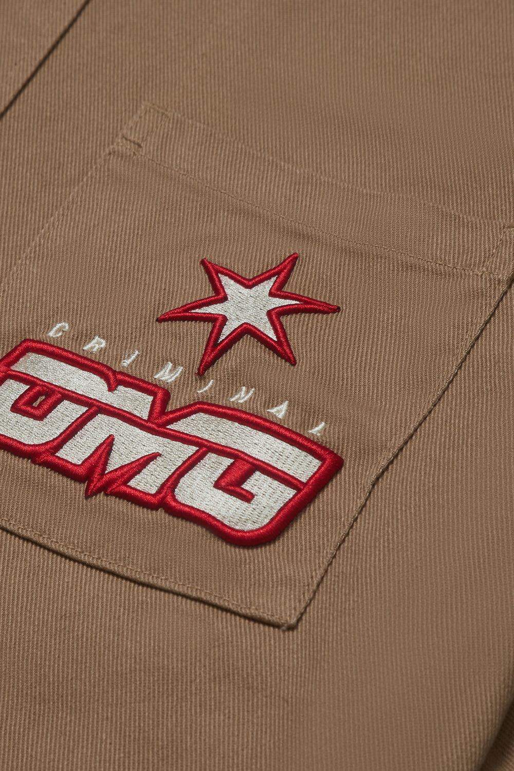 Close up of Criminal Damage embroidered patch on button up shirt