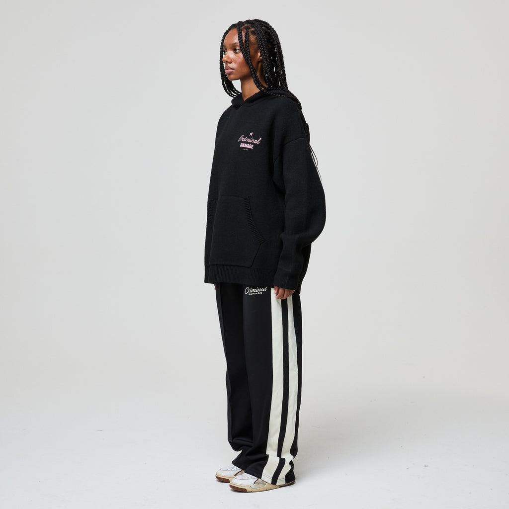 Person wearing a black tracksuit with white stripes on a white background