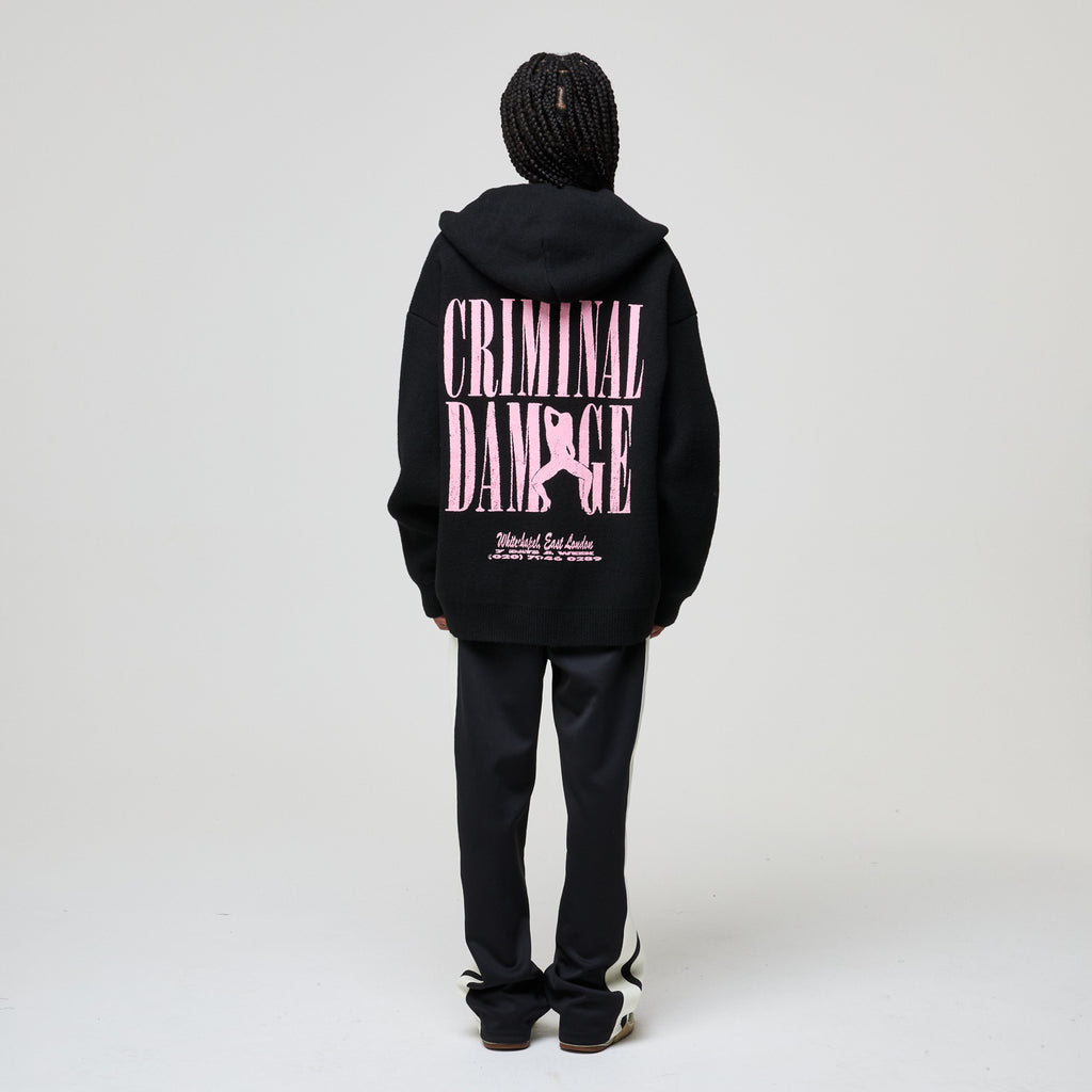 Person wearing a black hoodie with pink text on the back against a white background