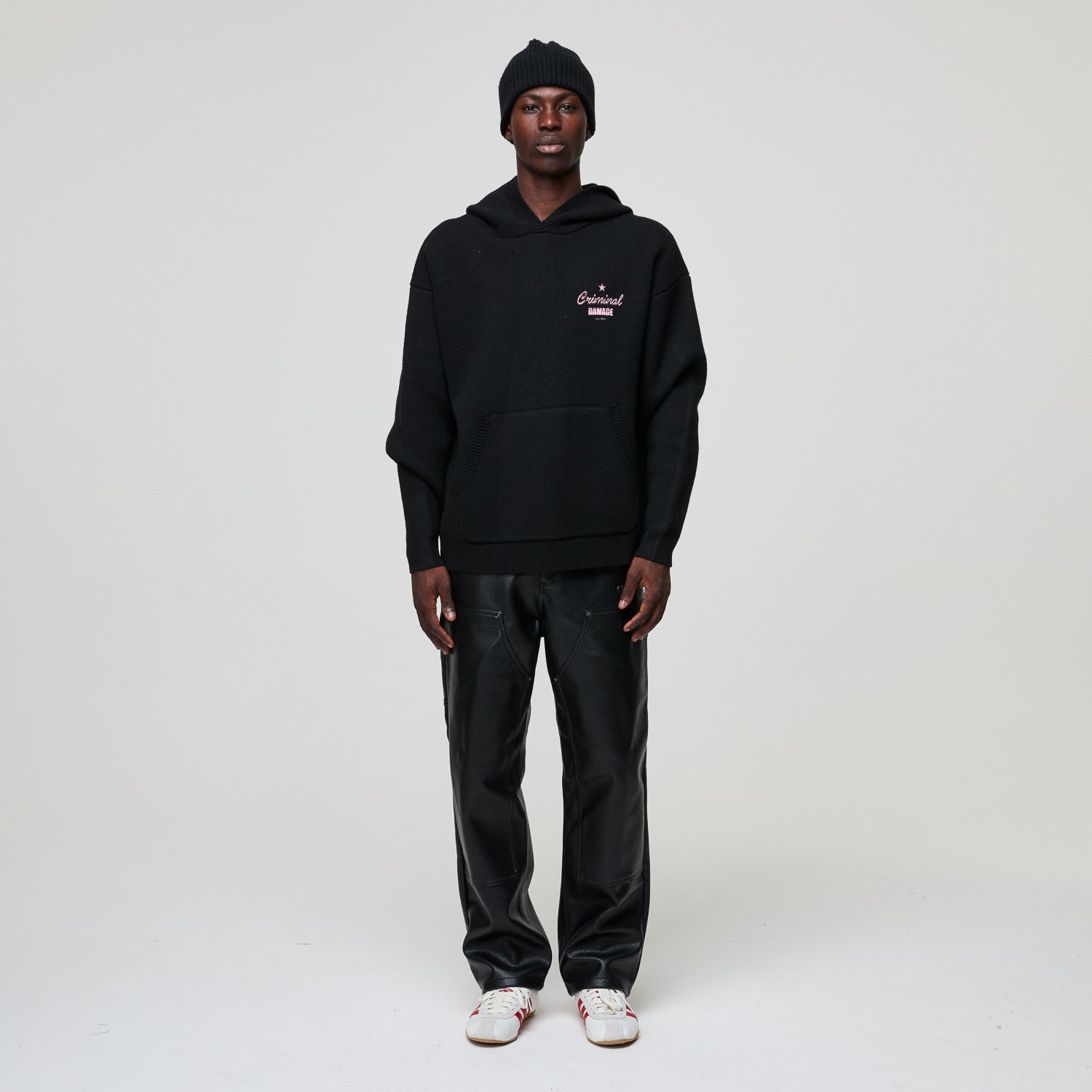 Person wearing a black hoodie and pants with a logo on a white background