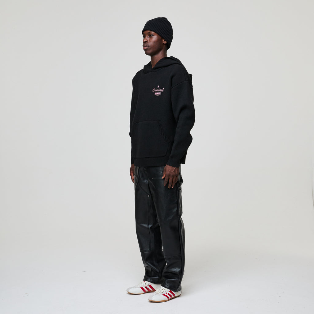 Person wearing a black hoodie and pants with white shoes on a white background