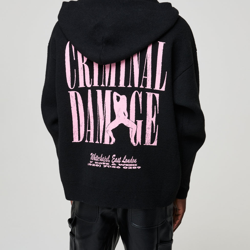 Black hoodie with pink 'Criminal Damage' text and graphic on a plain background