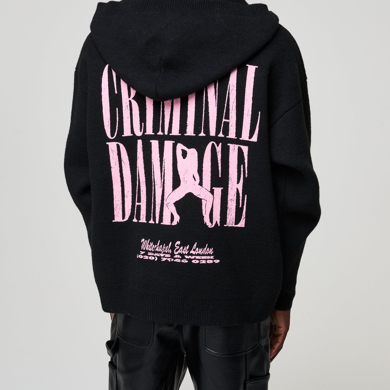 Black hoodie with pink 'Criminal Damage' text and graphic on a plain background