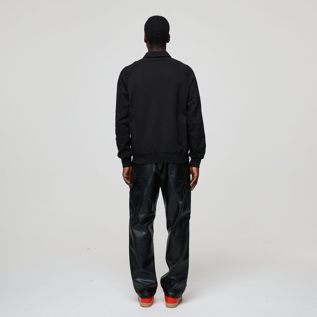 Person wearing a black Criminal Damage  jacket and black pants on a white background