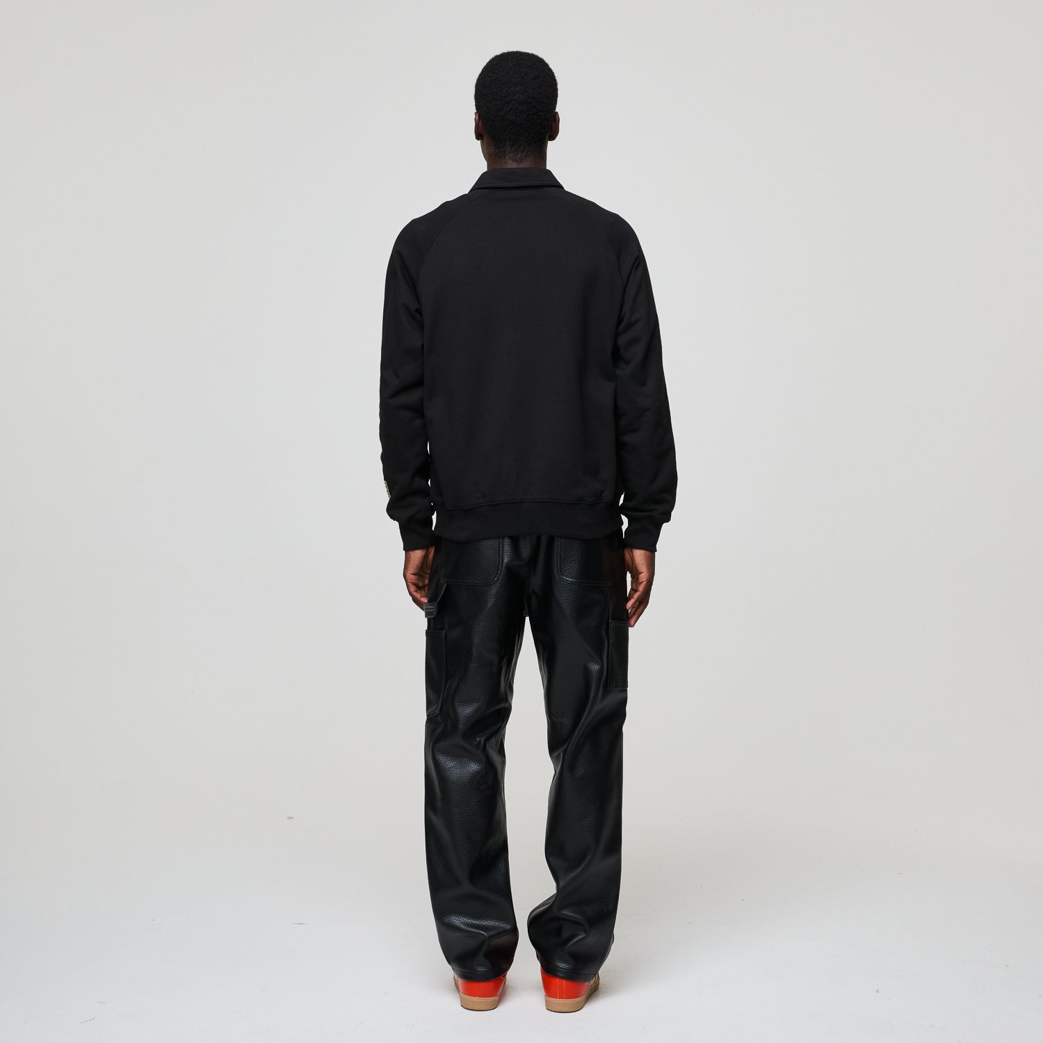 Person wearing a black Criminal Damage  jacket and black pants on a white background
