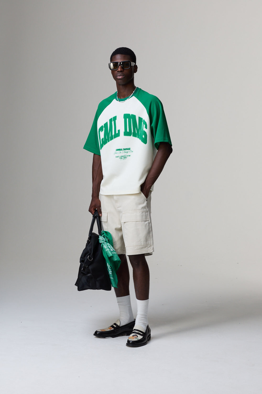 Model wearing a Criminal Damage green and white 'GAL DUG' t-shirt with beige shorts on a plain background