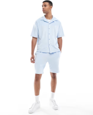 Man wearing a light blue shirt and shorts set on a white background