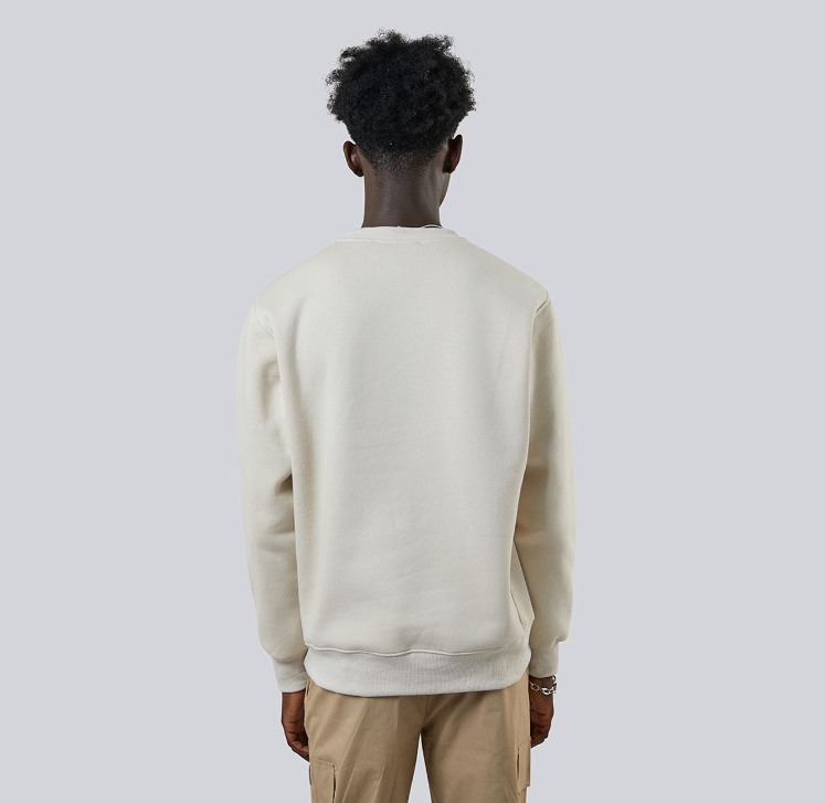 Person wearing a cream-colored sweater and beige pants against a plain background